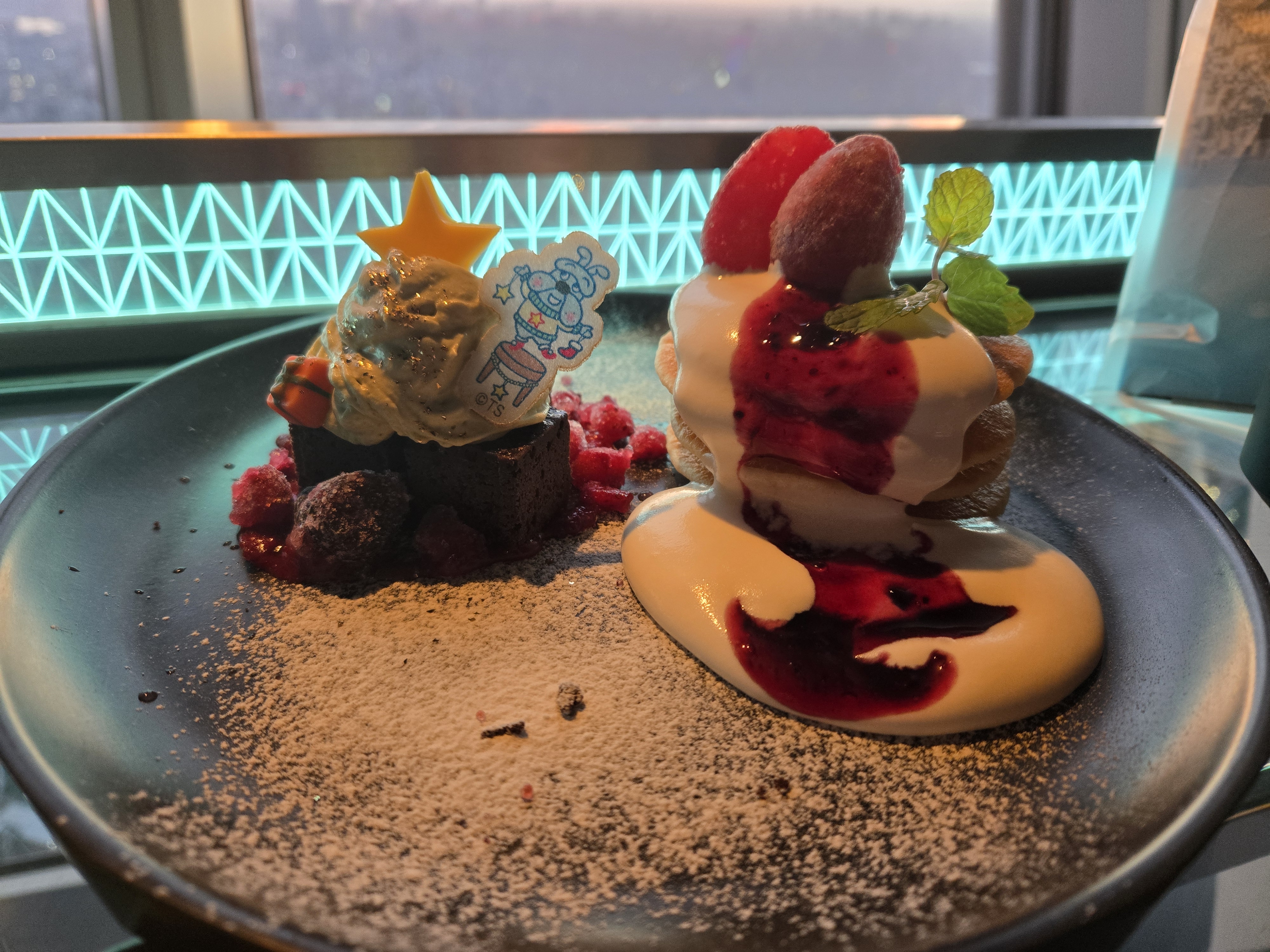 A photo of a small plate of chocolate brownies and miniature pancakes.