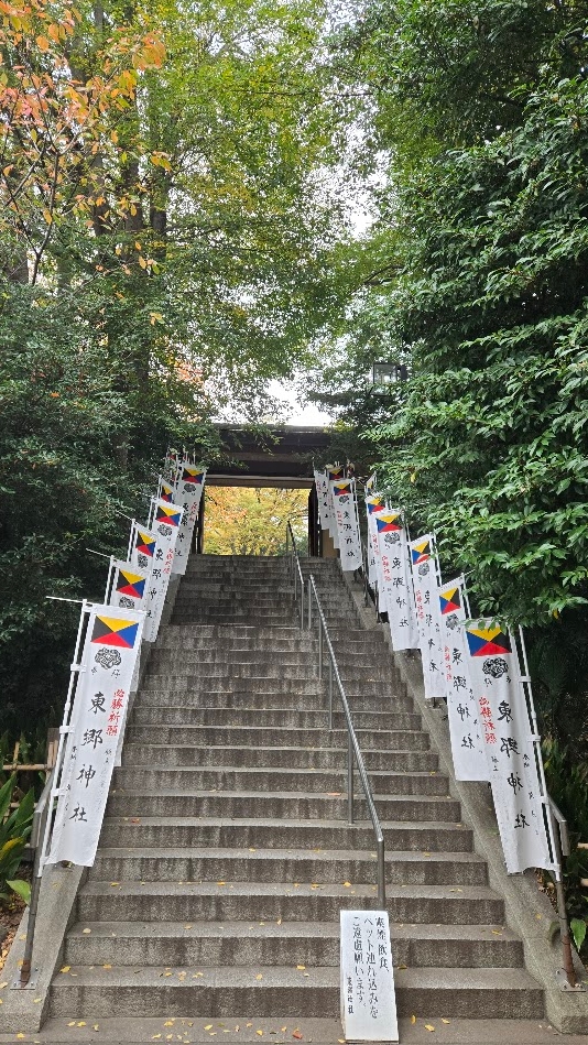 A photo of a stairway lined with greenery and religous flags.