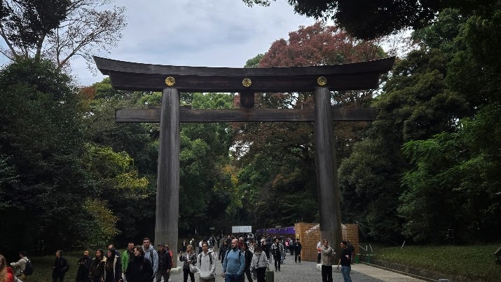 A photo of a giant torii gate towering over a road full of people.