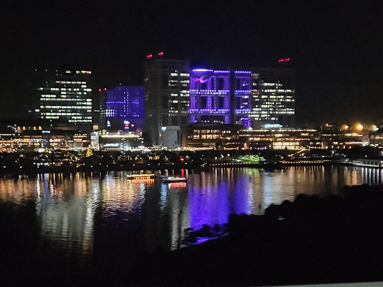 A photo of a waterline of buildings, lit up in various colours.